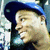 A person wearing a blue cap and dark clothing, smiling with mouth open, shown in four with slight head movement