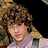 Pixelated image of a person with curly brown hair wearing a light purple shirt, with red text reading "I LOVE YOU NICK J!!!!" and "This is an SOS." on a black background.