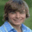 Pixelated static image of a person with light brown hair wearing a blue shirt against green background.