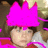 A person with brown hair wears a bright pink crown-like headpiece against a blurred background.