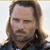 Static pixelated image of a person with long brown hair, beard, and mustache wearing dark clothing against a light background.