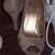 A golden bell-shaped object with a reflective surface and a dark base, positioned among other similar shapes on a dark background.