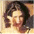 Pixelated image of a person with dark wavy hair against light background, adjacent to green with bright green text