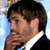 Static 50x50 pixel icon showing a close-up of a person's face and upper torso in formal attire against a light blue background with partial yellow text visible at the top left.