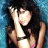 Pixelated static image of a person with dark hair wearing a black top, hands raised near face against blue background.