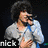 A person with curly hair sings into a microphone, wearing a light gray shirt and blue strap, with text 'nick' below.