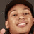 Pixelated close-up of a person with dark hair, light skin tone, and visible teeth in a smiling expression against a neutral background.