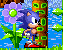 Pixelated Sonic the Hedgehog stands beside a brown tree trunk with green square patterns, next to a large purple flower with a green center.