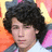 Pixelated portrait of a person with voluminous dark curly hair against a multicolored background featuring orange, pink, yellow, and blue hues.