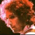 Pixelated close-up of a person with light brown hair and a pinkish hue on the left side, set against a dark background.