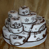 A multi-tiered cake with white frosting and brown decorative patterns, including floral motifs and scrollwork, arranged in a clustered, asymmetrical composition.