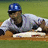 A baseball player in a blue helmet and gray uniform slides toward home plate on a grassy field, with red text overlays appearing sequentially.