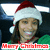 A person wearing a red and white Santa hat with a white pom-pom, smiling with visible teeth, against a dark background with green and blue elements.