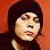 Pixelated close-up of a person with dark hair against an orange background, showing partial facial features and clothing.
