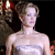Pixelated image of a person with light skin tone wearing a strapless white dress, standing against a dark background with red and brown elements.