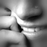Black-and-white close-up of a person's mouth and fingers with visible teeth, lips, and hand positioning near the face.