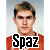 Pixelated portrait of a person with short brown hair wearing an orange shirt, overlaid with large black text reading "Spaz" on white background.