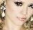 Pixelated close-up of a person's face with visible eyes, nose, and lips against a light background.