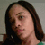 Pixelated close-up of a person with long dark brown hair, light skin tone, and visible facial features including eyes, nose, mouth, and ear against a neutral background.