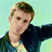 Pixelated image of a person with light brown hair wearing a dark jacket over a light shirt, set against a teal background with bold text.