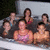 Group of people in a hot tub with one person in a pink top, others in dark clothing, and a white tub background.