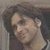Animated sequence showing a person with long dark hair in two poses: first facing left, then turning to face forward while holding a guitar.