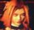 Pixelated static image of a person with light brown hair and closed eyes, wearing an orange garment against dark background.