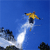 Pixelated static image of a yellow stick figure skiing with arms outstretched against a blue sky background, leaving a white trail behind it and showing partial dark shapes at the bottom left and right edges.