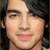 Pixelated close-up of a person's face with dark hair, light skin tone, and pink lips against a dark background.