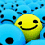 Yellow cartoon character with black eyes and mouth on blue background, surrounded by scattered dark pixels.