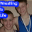 Two young men in blue wrestling singlets pose together with a blue text overlay reading "Wrestling is Life" in pixelated font.