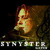 Pixelated image of a person singing into a microphone with 'SYNYSTER GATES' text below, set against a dark background with musical symbols.