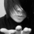Black-and-white image of a person with dark hair wearing a high-collared top, making a hand gesture near the face.