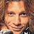 Two individuals with light brown hair appear in a static close-up, one wearing dark clothing with white accents.