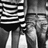 Black-and-white pixelated image showing a figure with striped shirt and dark pants, standing in front of a building with vertical lines.