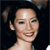 Pixelated close-up of a person with dark hair tied in a ponytail, smiling with visible teeth against a dark background.