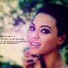 A static image of a person with short dark hair, wearing makeup, holding a cigarette near their mouth with a blurred background of green foliage and light-colored smoke.