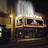 Pixelated image of a vintage cinema interior with a large screen, red and gold trim, and dark seating areas.