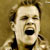 Static 50x50 pixel icon showing a close-up of a person's face with mouth open in an expressive gesture, set against a brown background.