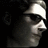 Pixelated grayscale profile of a person wearing a light-colored cap and dark sunglasses against a black background.