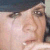A pixelated close-up of a person's face with light skin tone, dark hair, and visible eyes and nose, set against a dark background.