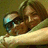 A pixelated image shows a person with brown hair lying down, wearing dark sunglasses and holding a light-colored object near their face.
