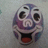 Purple cartoon face with wide eyes, open mouth showing red tongue, and white eyebrows on light gray background.