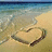 Pixelated beach scene with calm water, sandy shore, and a heart shape drawn in the sand.
