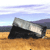 A pixelated landscape featuring a large rock formation on sandy ground under a blue sky with horizontal stripes.