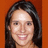 Pixelated portrait of a person with long dark hair against an orange background, smiling with visible teeth.