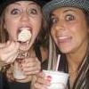 Two people in close-up pose with one holding a cup and the other holding a round object near their mouth.