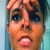 Pixelated close-up of a person's face with light brown hair, blue eyes, and an open mouth expression against a gradient background.
