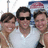 Three people in a group pose, one wearing sunglasses and white shirt, against light background with blue and pink shapes.