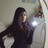 Pixelated static image of a person with long dark hair holding a bright light source, standing against a muted background.